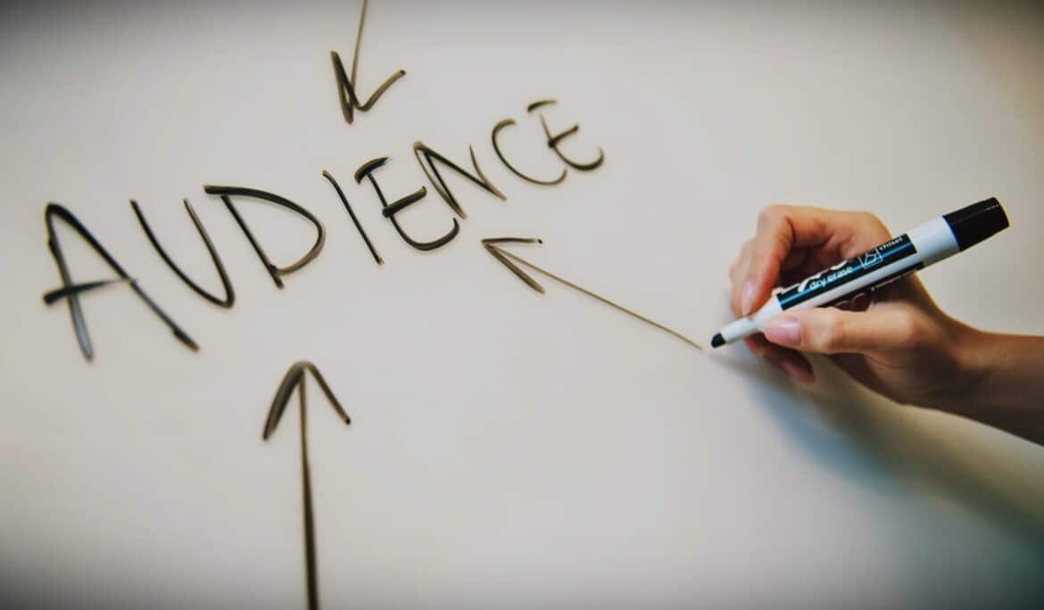 An individual engaging in experiential marketing by writing the word "audience" on a whiteboard.