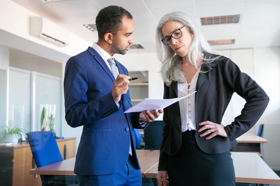 serious-colleagues-discussing-project-document-signing-female-grey-haired-manager-eyeglasses-listening-boss-partners-working-meeting-room-teamwork-business-management-concept_74855-7789