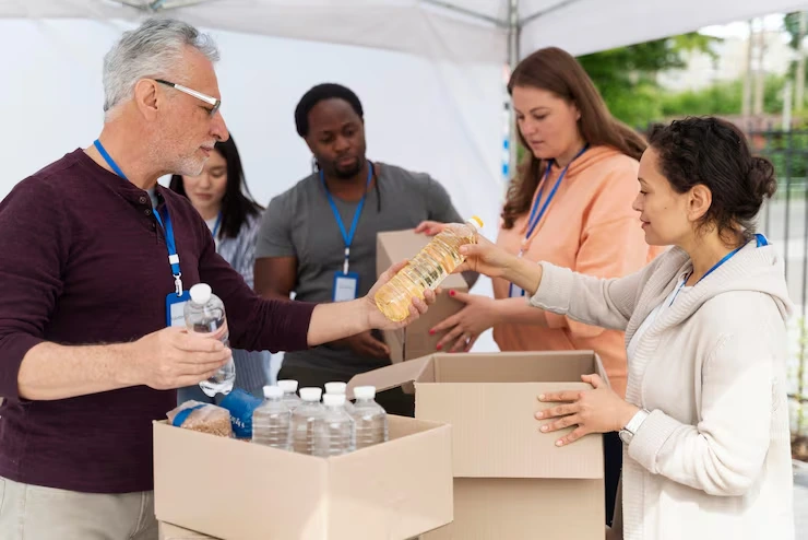 Volunteers organizing donation supplies at outdoor charity event with water bottles and relief packages