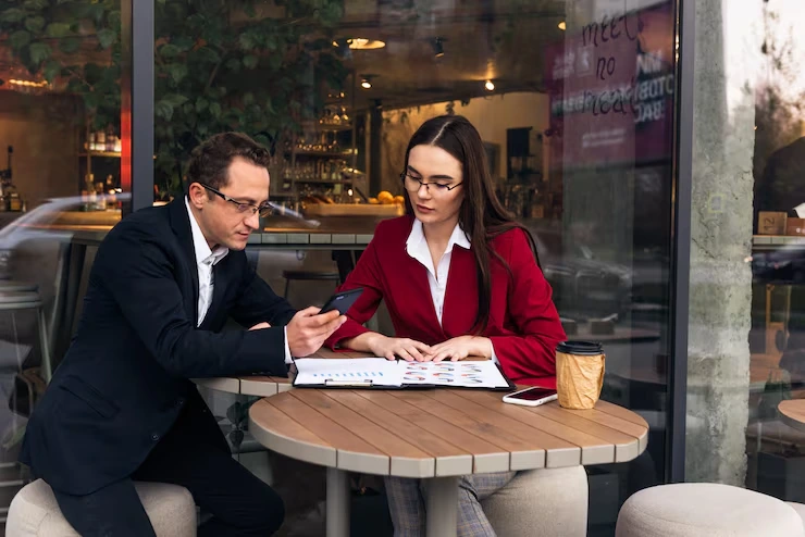 Business professionals reviewing event proposals at modern Barcelona café with documents and coffee