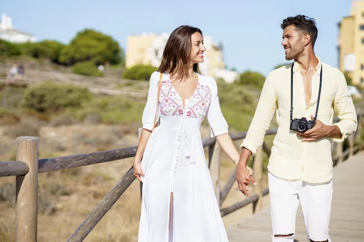 Happy couple walking hand in hand along coastal pathway with photographer capturing their Lisbon wedding