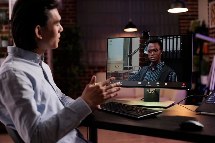 Professional conducting virtual meeting with remote participant on laptop screen in modern office setting