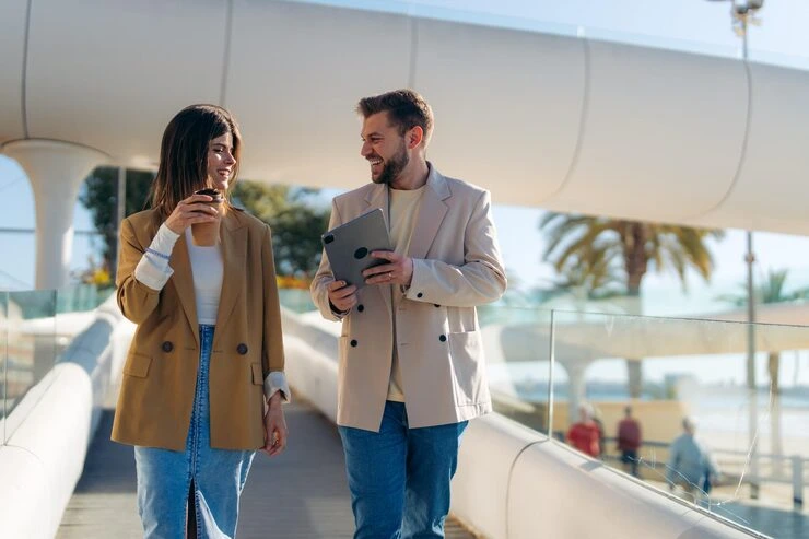 Event management professionals discussing industry trends on modern Barcelona waterfront with digital devices