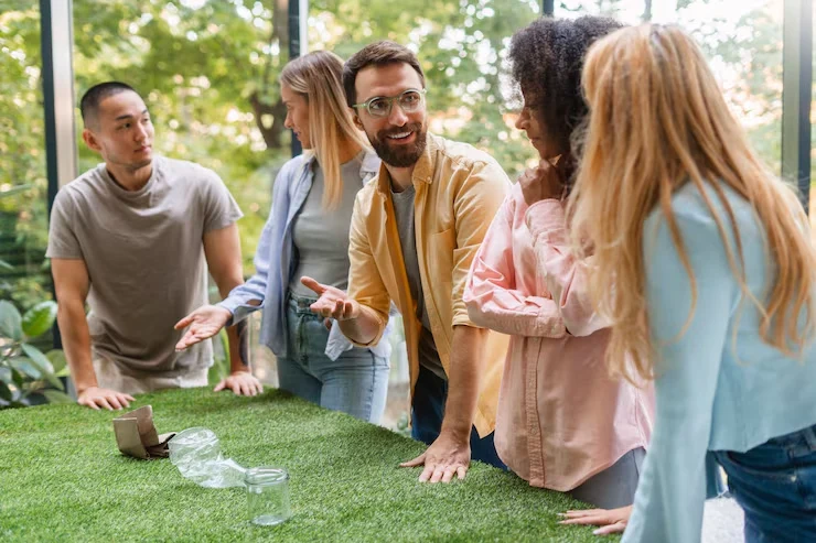 Five colleagues participating in interactive team building activity on artificial grass in bright modern space