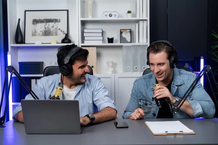 Two hosts recording professional podcast with microphones, headphones and laptop in modern studio setup