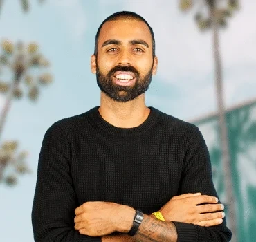 Deepak Shukla, founder, smiling outdoors with palm trees in background