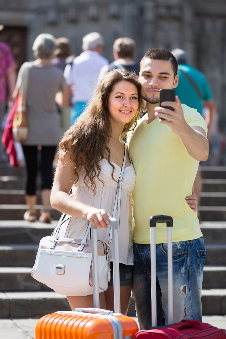 Event Management Company in Budapest, Hungary for Corporate and Private Events Couple taking selfie with luggage at historic Budapest landmark on sunny day