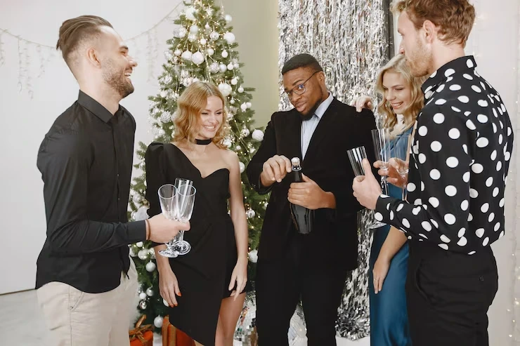 Five guests in formal attire celebrating with champagne at elegant holiday party with decorated tree