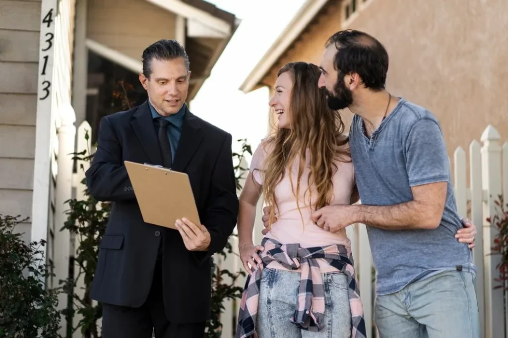 Event coordinator reviewing checklist with smiling couple outside residential venue on sunny day