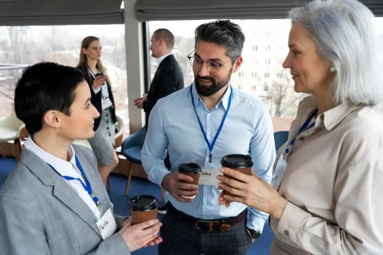 Three badged professionals chatting over coffee cups
