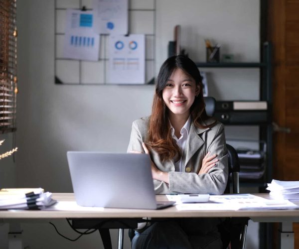 business Asian woman working online at home office and looking at the camera.