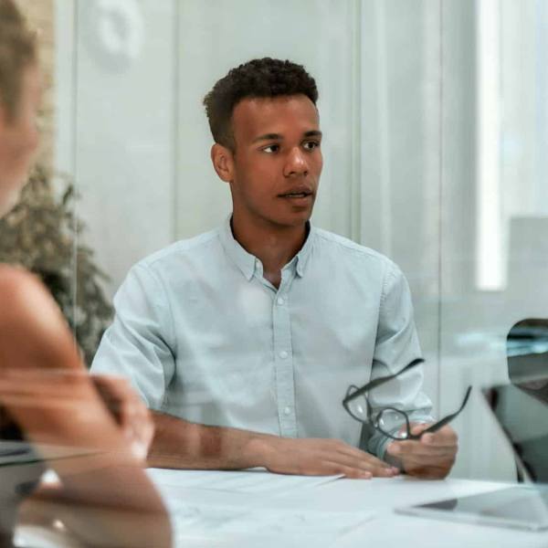 Business expert. Young afro american man holding eyeglasses and explaining something to his