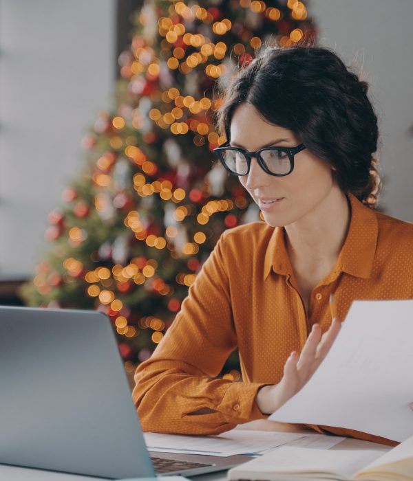 Hispanic business lady in glasses working online in office on Christma