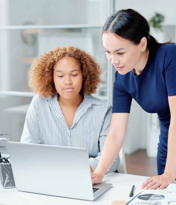 One of young businesswomen making presentation or helping colleague