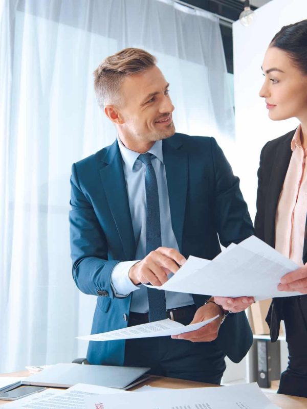 smiling business colleagues doing paperwork at workplace in office,