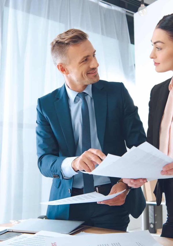 smiling business colleagues doing paperwork at workplace in office,