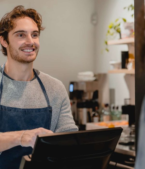 Smiling helpful young waiter servicing the customer at cash point in cafe, Best Creative Agency London