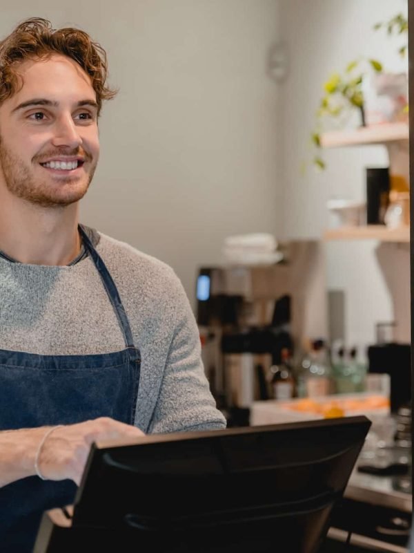 Smiling helpful young waiter servicing the customer at cash point in cafe Smiling helpful young waiter servicing the customer at cash point in cafe, Best Creative Agency London