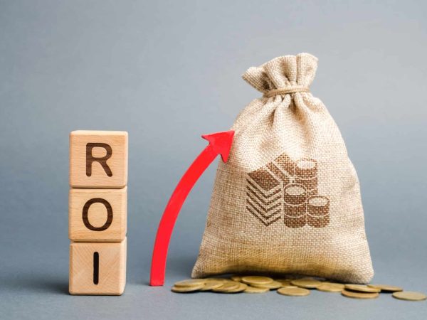 Wooden blocks with the word ROI and the up arrow with the money bag increase ROI